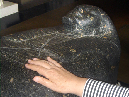 Mano che tocca un sarcofago egizio originale al British Museum di Londra.